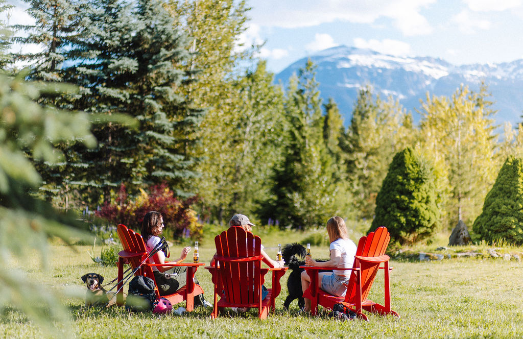 A group of friends gather in Muskoka chairs at Glacier House Resort