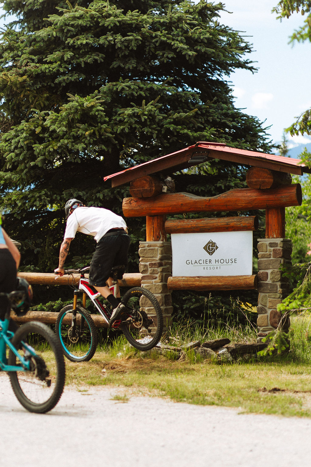 A cyclist in front of the Glacier House Resort sign
